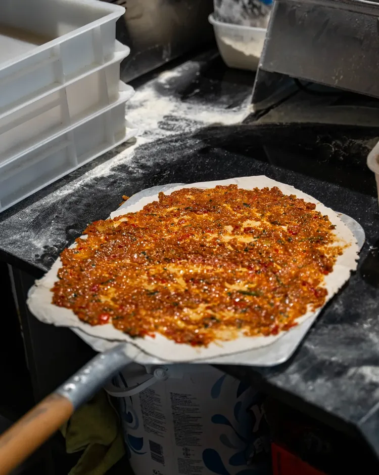 Frisch belegter Lahmacun auf dem Holzschieber in der Backstube