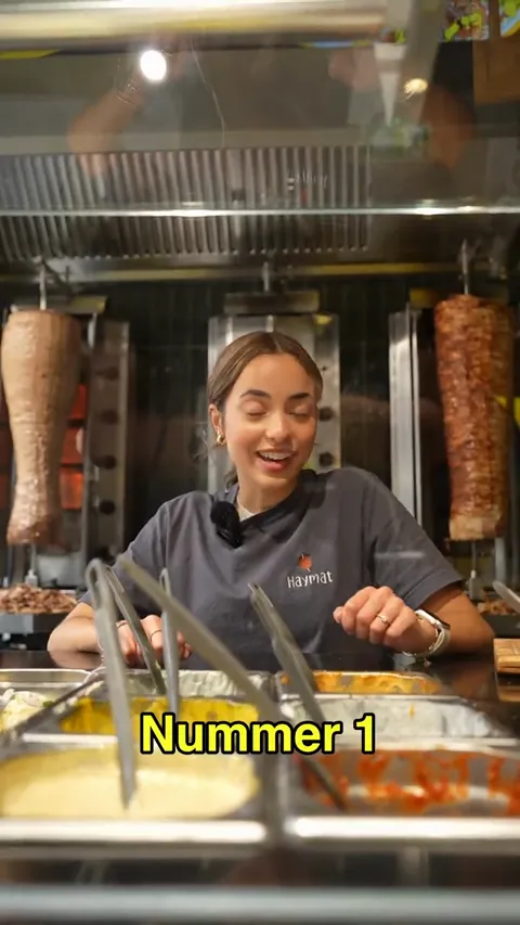 Reel-Standbild: am Spieß hinter der Theke, im Vordergrund die Toppings